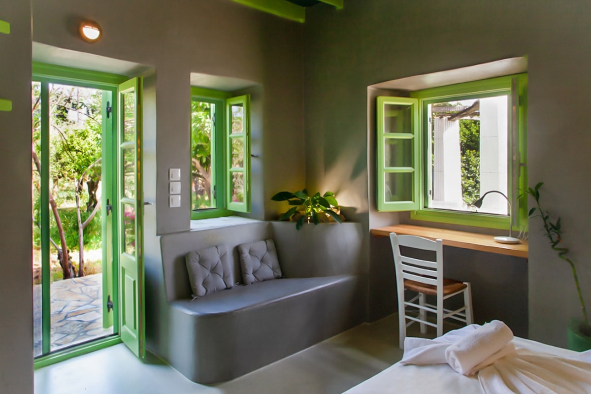 Bright bedroom in the studio with green door and windows, and a built-in couch.